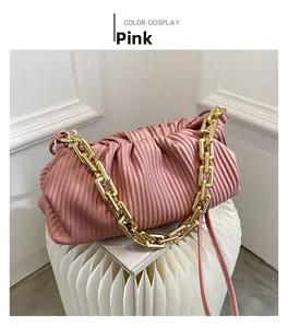 Close-up of pink pleated cloud bag featuring chunky gold chain strap on design stool