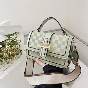 Close-up of light green checkered crossbody bag with golden H clasp and wide strap