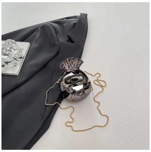 Macro view of silver mirror metal shell bag with gold chain and pleated opening