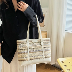 Striped straw tote bag with white leather trim and handles shown in a lifestyle setting