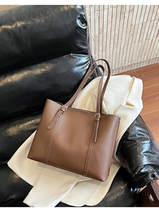 Dettaglio borsa tote marrone con cuciture a contrasto bianche e fibbie dorate raffinate