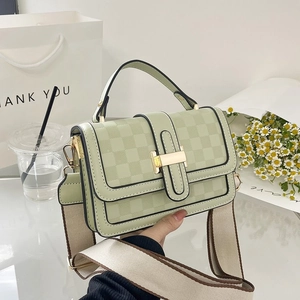 Detail of mint green plaid embossed crossbody bag with wide woven strap and gold buckle