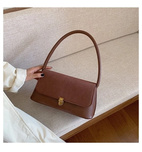 Detail view of deep brown leather baguette bag with suede flap and gold metal buckle
