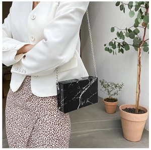 Detail view of black marble pattern box bag with silver metal chain and lock