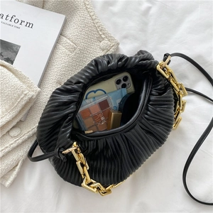 Detail view of black pleated cloud bag with chunky gold chain and spacious interior