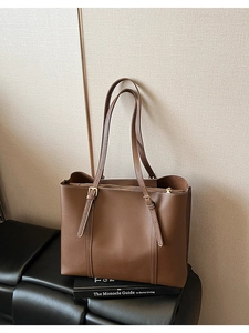 Dettaglio della borsa tote in pelle marrone scuro con cuciture bianche e fibbie metalliche