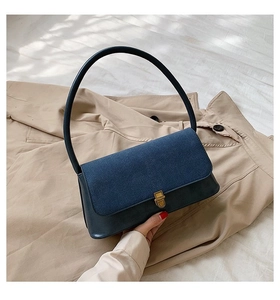 Detail of vintage navy blue shoulder bag with golden buckle and textured suede flap cover