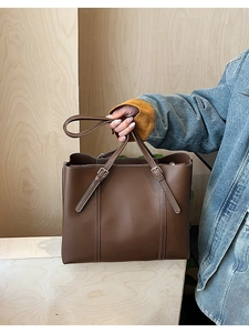 Dettaglio della borsa tote vintage in pelle marrone con cinturini regolabili e cuciture bianche