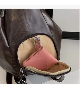 Detail view of the brown leather backpack front zipper pocket showing storage capacity