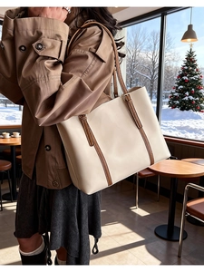 Dettaglio della grande borsa tote crema con manici marroni in un caffè accogliente