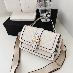 Detail of cream white quilted handbag with golden H-buckle and wide woven shoulder strap