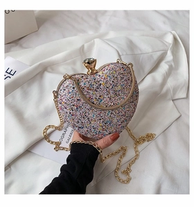 Detailed view of heart-shaped glitter evening clutch with gemstone clasp and gold chain