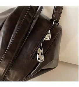 Detail view of smooth dark brown leather texture and silver side zipper of the backpack