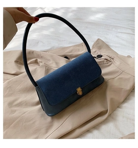 Detail of retro navy shoulder bag with denim texture flap and gold metallic twist lock