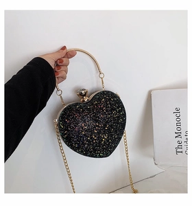 Macro shot of heart-shaped glitter clutch bag with gold ring handle and crystal clasp