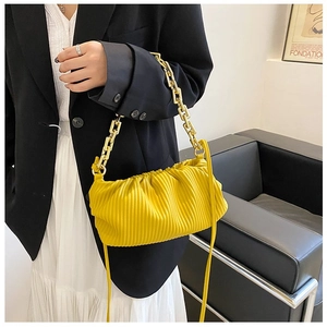 Close-up of a bright yellow pleated cloud bag with chunky gold chain and leather strap