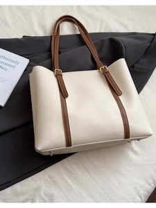 Dettaglio della borsa tote beige vintage con cinturini in pelle marrone e piedini in metallo