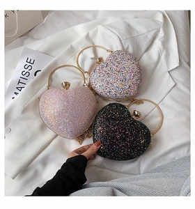 Three sequined heart-shaped clutch bags in pink, white and black with gold metal handles