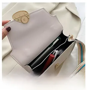 Dettaglio dell'interno della borsa a tracolla color crema con scomparti per smartphone e rossetto