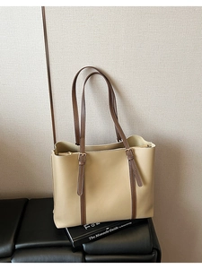Dettaglio della borsa tote beige con manici marroni e fibbie metalliche regolabili