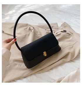 Detail of black leather handbag with a large round handle and golden twist lock