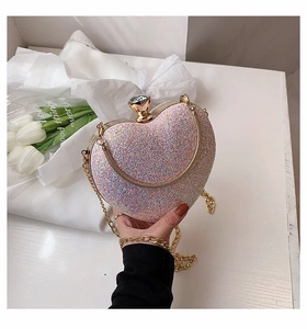 Close-up of pink glitter heart clutch with gold chain and diamond clasp detail