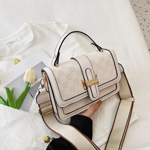 Close-up of cream crossbody bag featuring checkered texture and wide woven strap