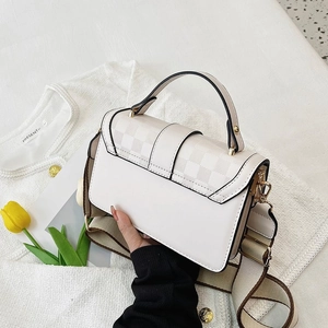 Close-up of the cream crossbody bag featuring a checkered flap and wide fabric strap