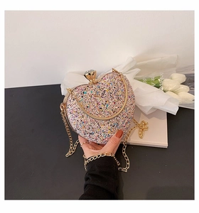 Detailed macro of heart-shaped glitter evening clutch with crystal lock and gold chain