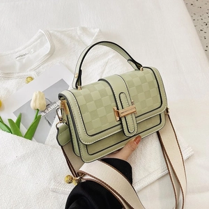 Close-up of light green crossbody bag with checkered texture and gold twist lock