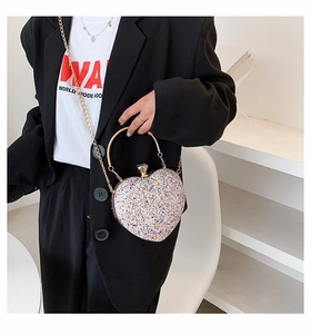 Detailed close-up of heart-shaped handbag with glitter sequins and gold metal handle