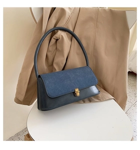 Detail of vintage denim and leather handbag with a golden metallic twist lock