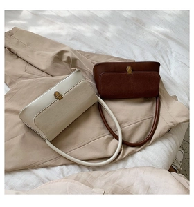 Detail of cream and brown retro leather underarm bags with golden metal buckle clasp