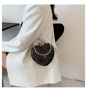 Detailed view of heart-shaped clutch with black sequins and gold chain strap accessory