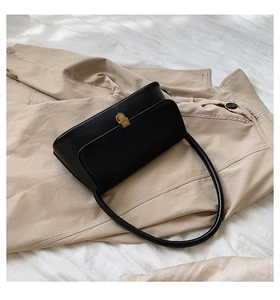 Close-up of black leather underarm bag with gold metal buckle on a trench coat