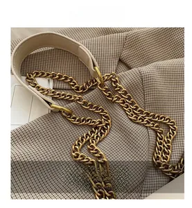 Close-up of vintage gold metal chain and cream leather strap on a small crossbody bag