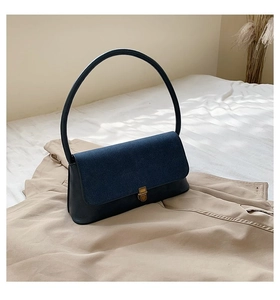 Detail of minimalist contrast handbag with navy suede flap and golden rotary metal lock