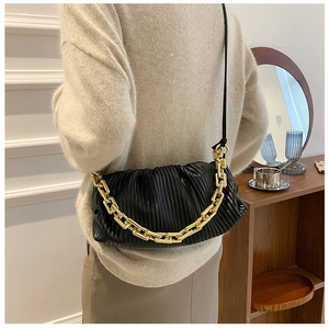 Detail of black pleated cloud bag with chunky gold chain and leather strap