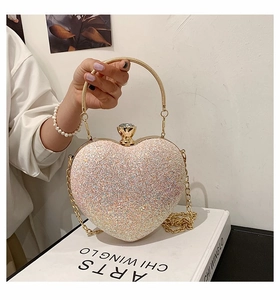 Detail of pink glitter heart-shaped evening bag with gold ring handle and jewel clasp