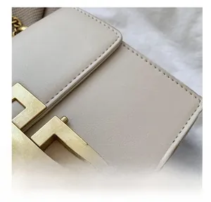 Close-up of a cream leather handbag featuring a vintage gold metal lock and neat stitching