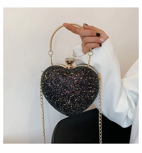 Macro shot of heart-shaped evening bag with colorful sequins and golden metal handle