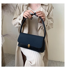 Detail of minimalist black faux leather handbag with vintage gold square buckle lock