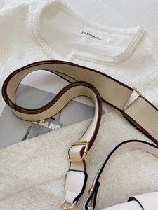Close-up of adjustable beige and brown woven bag strap with luxury gold metal hardware