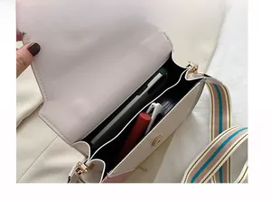 Vista interna della borsa a tracolla beige con tracolla a righe e scomparti interni