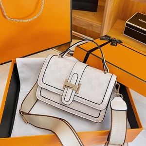 Close-up of white embossed crossbody bag with golden H-buckle and wide fabric strap