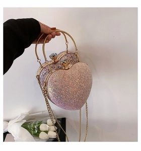 Detail of heart-shaped evening bag with pink sequins, gold ring handle and diamond clasp