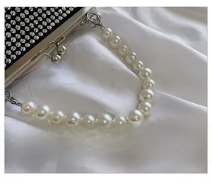 Detail of black evening clutch bag with sparkling rhinestones and large pearl handle