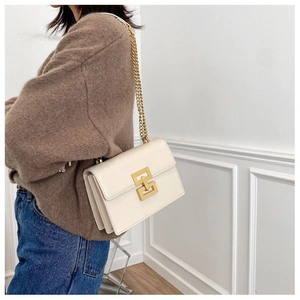 Detail of cream leather crossbody bag with gold chain strap and interlocking buckle