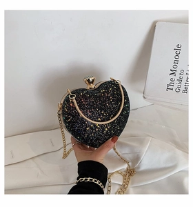 Detail of heart-shaped black glitter clutch with gold chain and diamond clasp