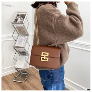 Detailed back view of a brown leather shoulder bag with a gold geometric lock and chain strap